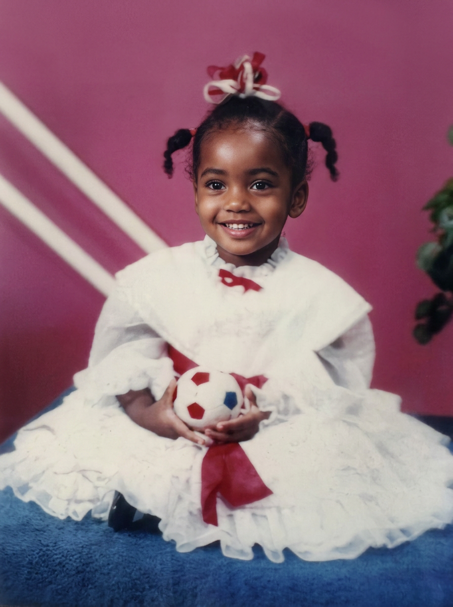 Jeneé as a little girl in a white dress